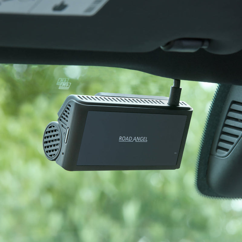 Car dashboard with a Road Angel device mounted on the windshield.
