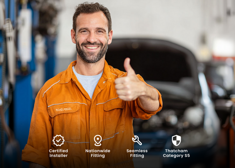 Mechanic in an orange jumpsuit giving a thumbs up in a car repair shop with certification icons below.