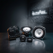 A set of black and silver audio speakers and subwoofers arranged on a dark reflective surface, with the brand name 'IN PHASE' illuminated in the background.