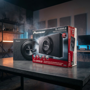 Pioneer TS-A3000LB subwoofer shown next to its retail box on a dark table in a dimly lit room with soundproofing panels on the wall.